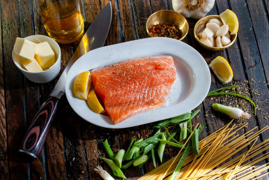 piece of fresh salmon a and spices on brown wooden table